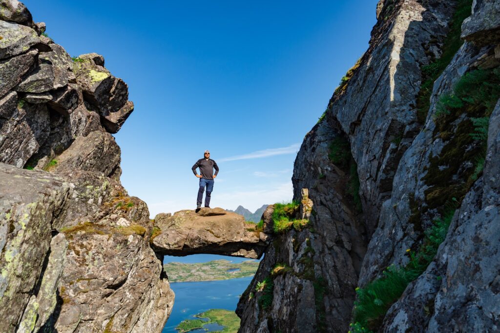Active Senior tourist man hiking at the beautiful Rock stuck in mountains Djevelporten. Norway. Happy pensioner climbing a mountain. Scandinavian tourism. Enjoying the outdoor leisure activity lifestyle