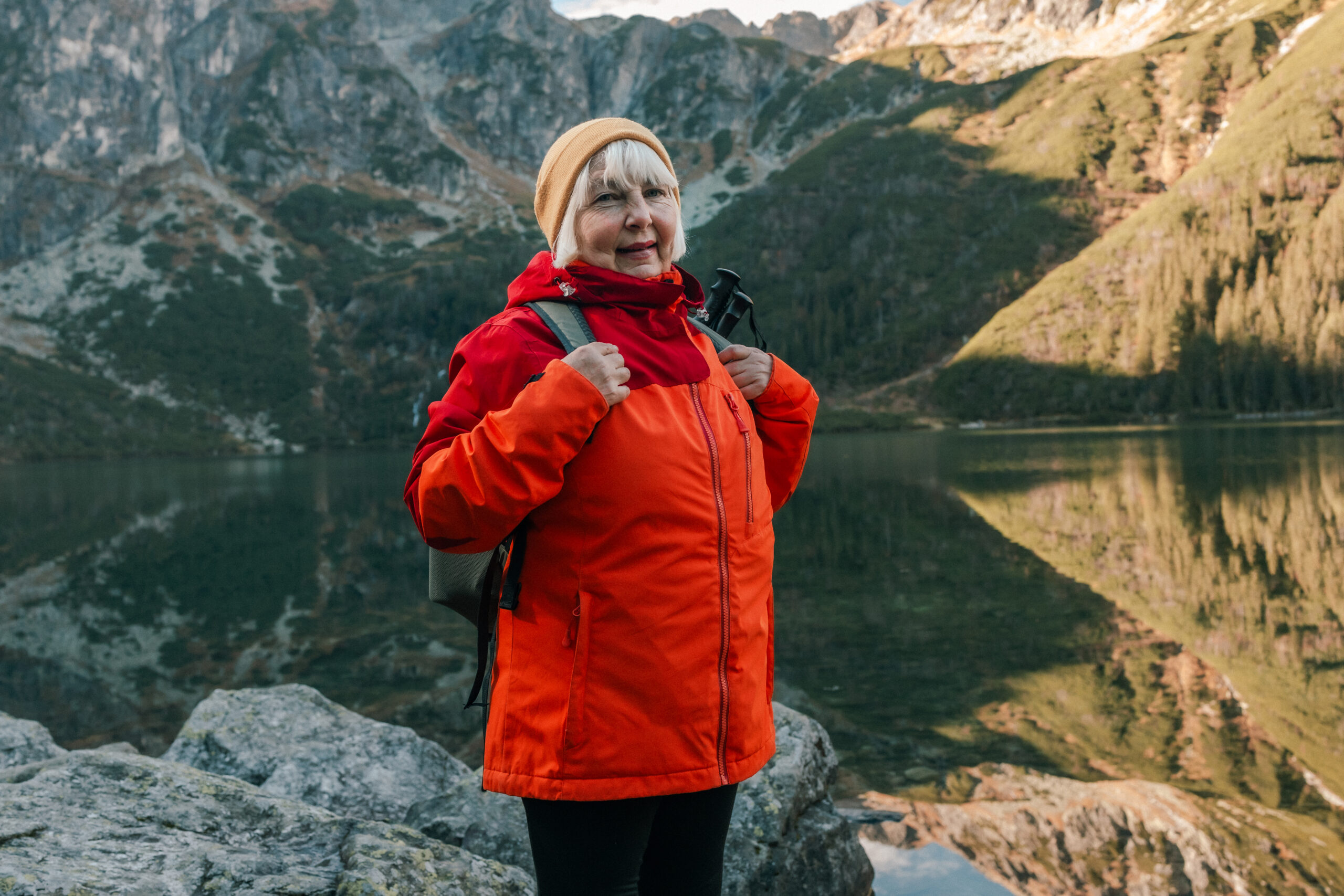 Lady tourist with a backpack standing on top of the mountain and enjoy the beautiful view of mountains Morskie Oko lake. Hiking travel and adventure in Poland, Tatry