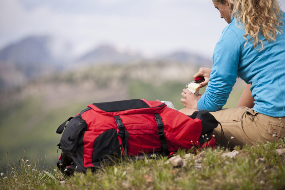Young woman sitting on grass with red backpack