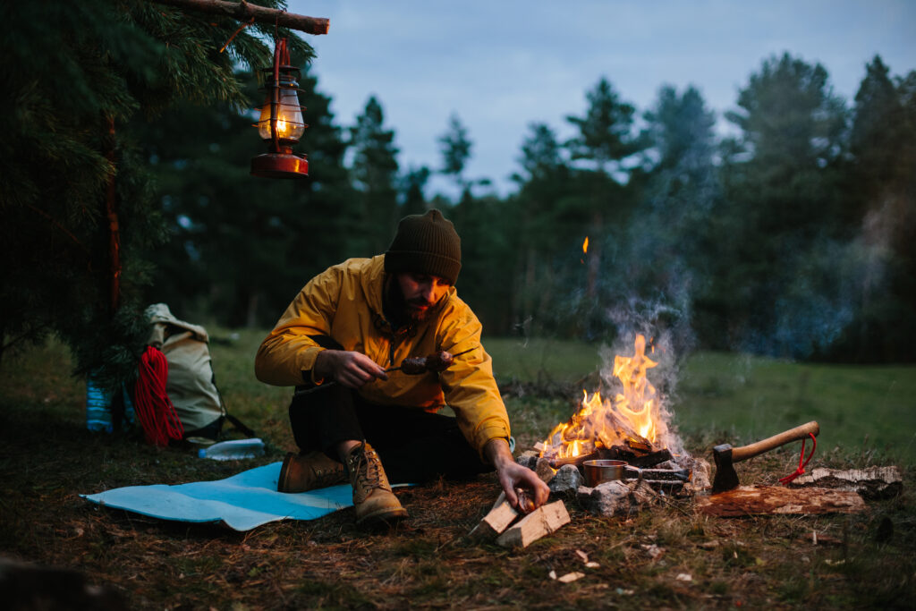 A lonely wanderer is having dinner in the mountains by a campfire.
